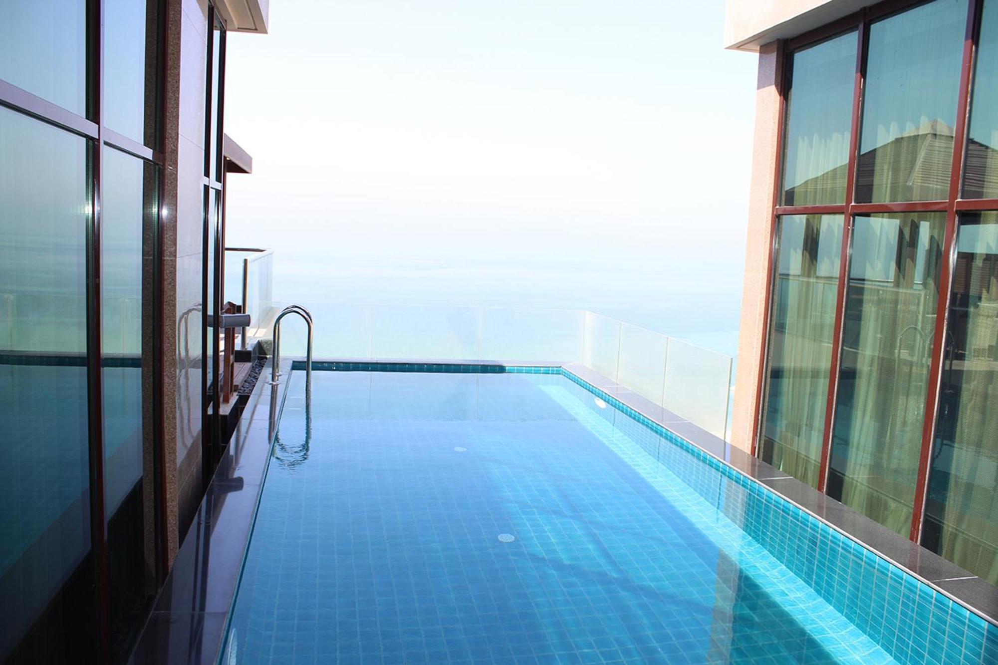 מנאמה Lagoona Beach Luxury Resort And Spa מראה חיצוני תמונה The photo shows an infinity pool situated on a balcony or rooftop, with a clear view extending to the horizon. The pool has a sleek design with blue tiles, and it appears to be reflecting the sky. There is a ladder on one side for access into the poo