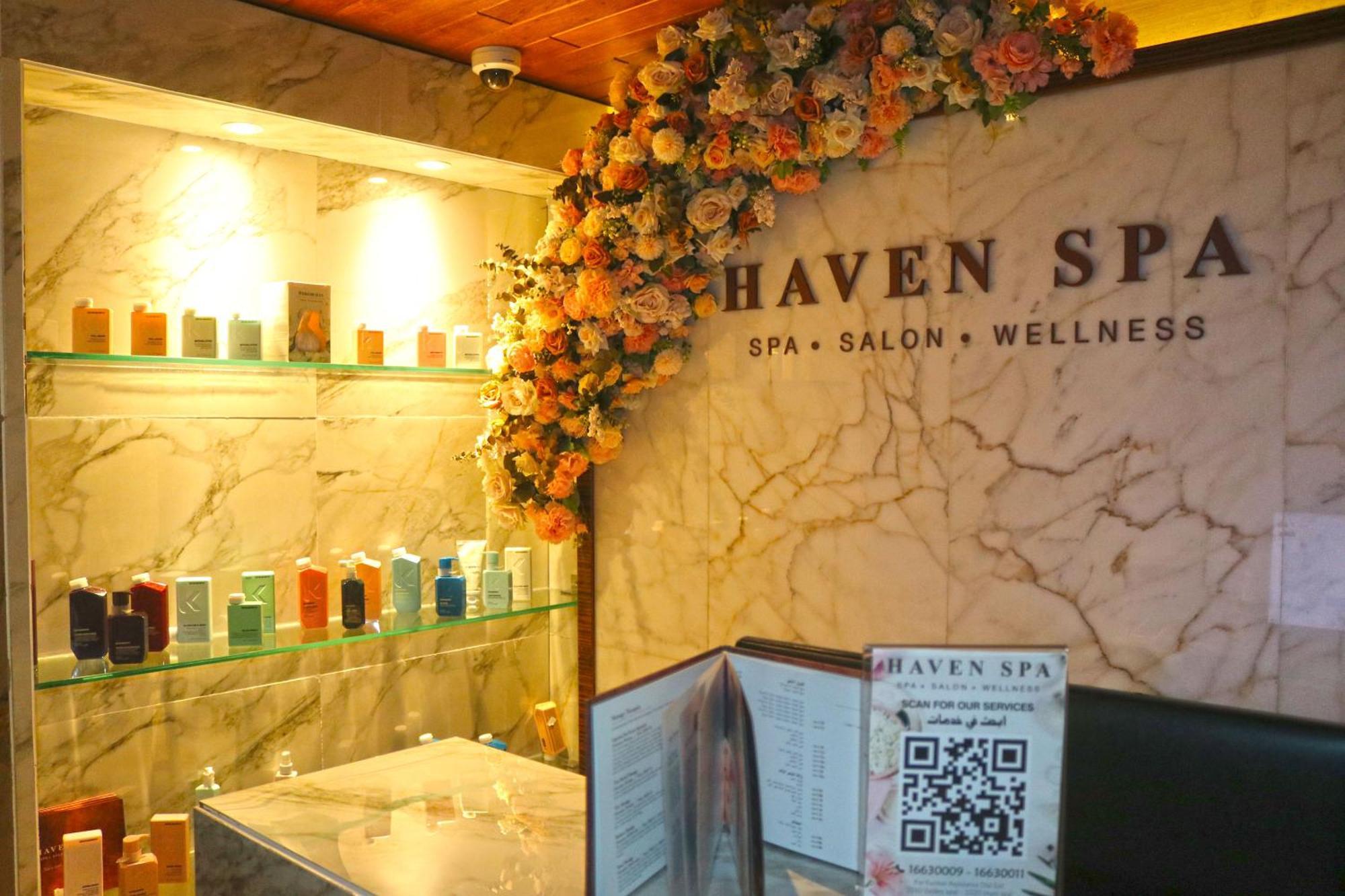 מנאמה Lagoona Beach Luxury Resort And Spa מראה חיצוני תמונה The photo shows the interior of a spa called "Haven Spa." The wall is decorated with beautiful artificial flowers, creating an inviting atmosphere. There are several shelves displaying various colorful bottles and products, likely for skincare or wel