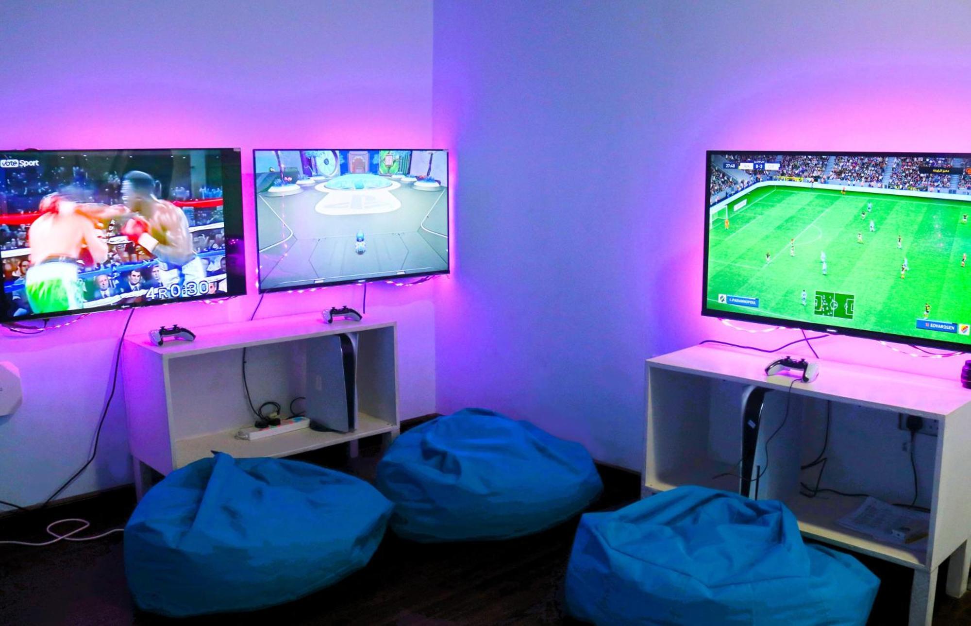 מנאמה Lagoona Beach Luxury Resort And Spa מראה חיצוני תמונה The photo shows a gaming area featuring three televisions mounted on the wall, displaying different games. Two of the TVs are showing gaming scenes, with one depicting a boxing game and the other showing a vibrant game environment. The third TV displ